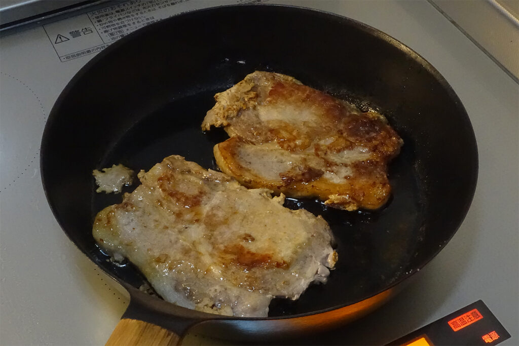 VERMICULAR FRYING PAN #24深型のフライパンで豚ロース肉を焼いている様子。表面に焼き色が付き、ジュワッと音を立てながら香ばしく仕上がっていく。