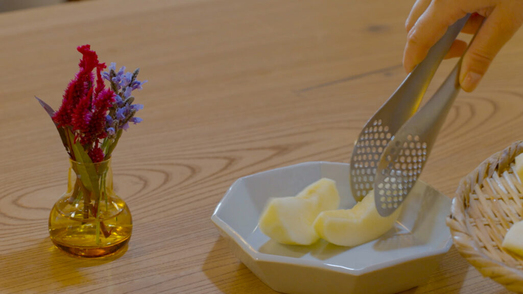 自宅で切ったリンゴをお皿に並べ、自然光の中で彩りよく盛り付けている様子。赤い実の瑞々しさが伝わる食卓の一瞬