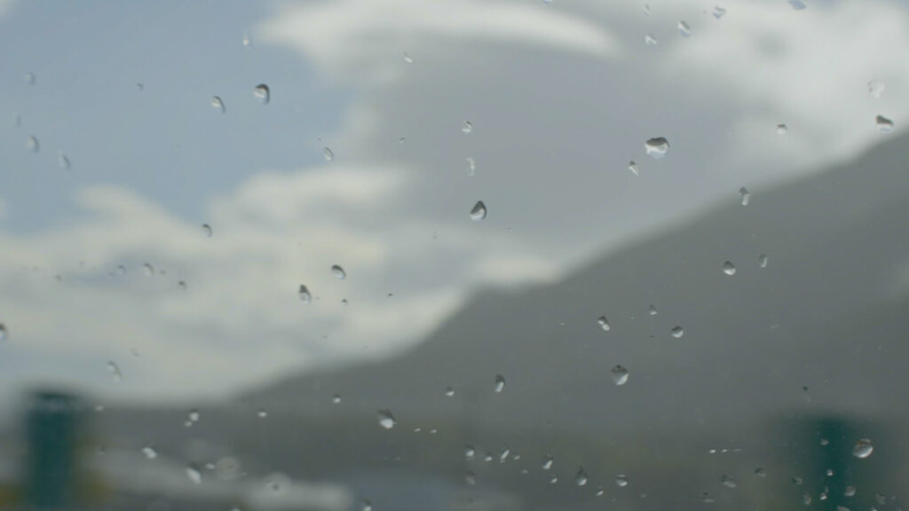 車のフロントガラスに雨の雫がつき、長野へ向かう山道を進む様子