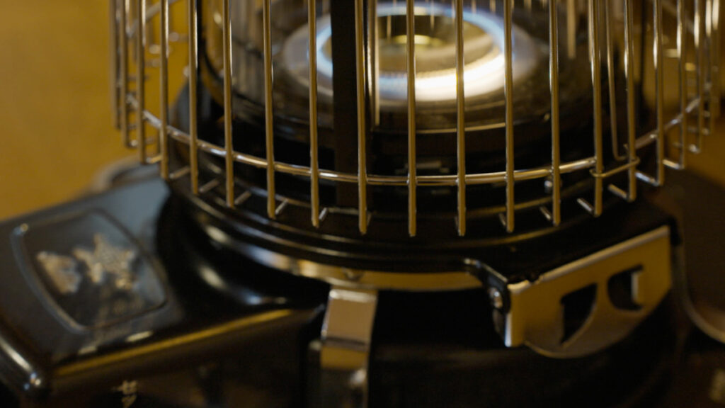 室内でストーブに点火したあと、本体上部を閉じて炎を落ち着かせ、冬じたくの手順を丁寧に進めている場面