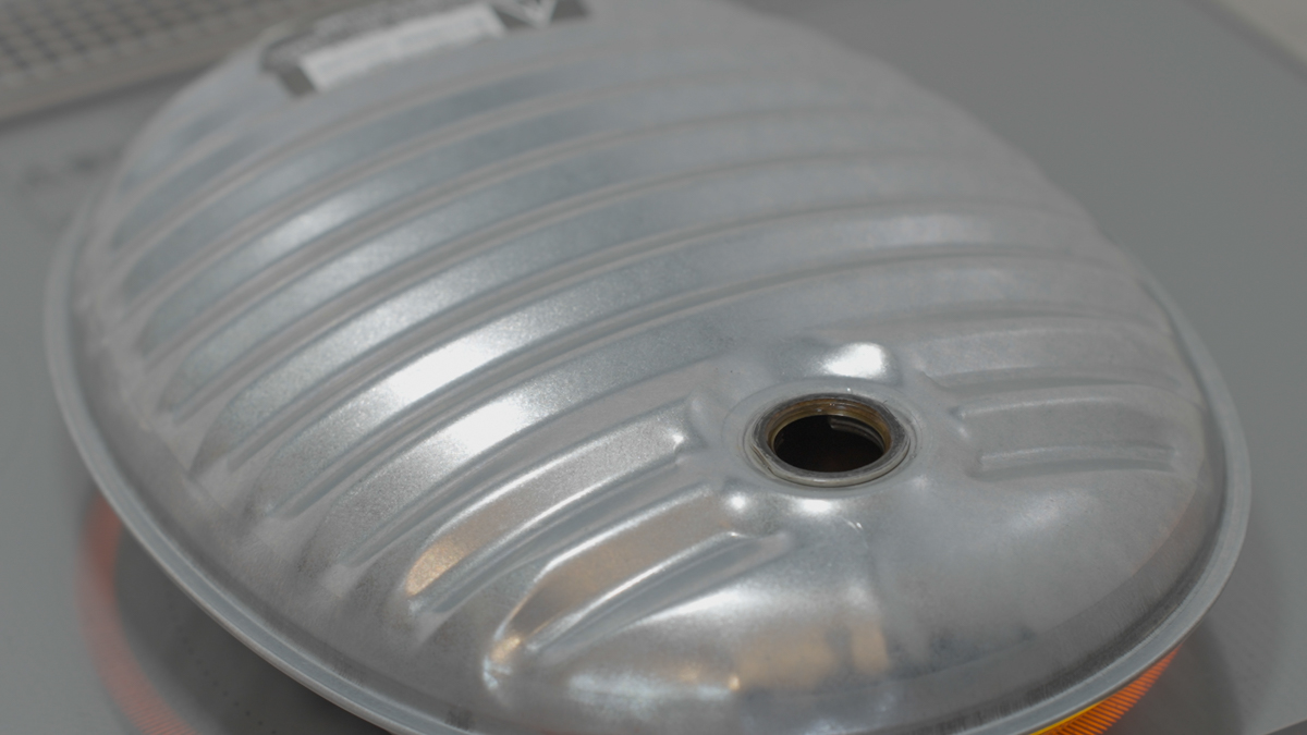 マルカの金属製湯たんぽをIHクッキングヒーターで温めている様子。手元に布巾を添えてやけどに注意しながら、冬の夜に備えて準備しているシーン