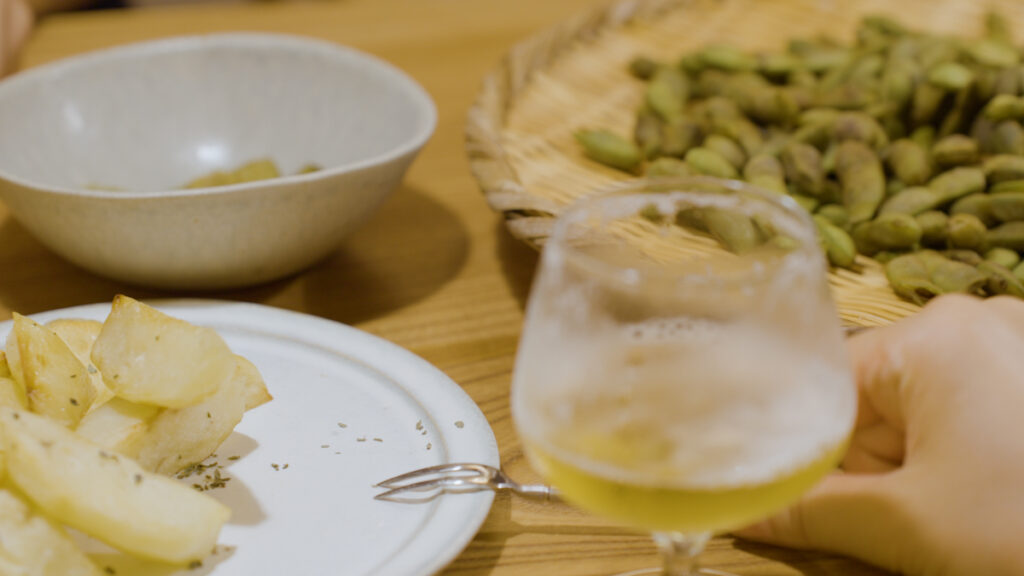 枝豆とポテトフライ、パインビネガーをビールと合わせた飲み物が並ぶ木のテーブル