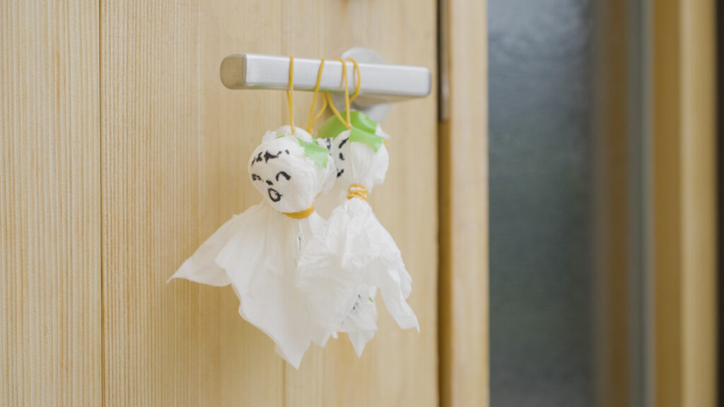 木製のドアの取っ手に、白い布で作ったてるてる坊主が吊るされている